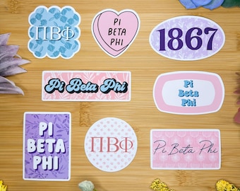 May include: A set of nine stickers featuring the Greek letters Pi Beta Phi in various designs. The stickers are in pink, blue, and purple with floral patterns. Some stickers include the year 1867 and the words "Pi Beta Phi".