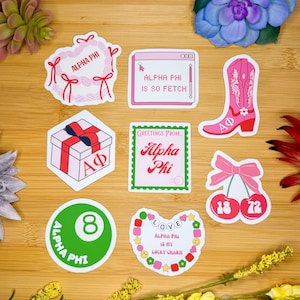 May include: Nine stickers featuring a variety of designs related to the sorority Alpha Phi. The stickers feature a heart wreath, a computer screen, a cowboy boot, a gift box, a stamp, a cherry, a pool ball, and a charm bracelet. The stickers are all pink, red, and green.