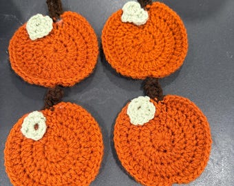 Puede incluir: Cuatro posavasos de calabaza hechos a mano con ganchillo. Cada posavasos es naranja con un tallo marrón y una hoja verde claro. Los posavasos son redondos y tienen un aspecto texturizado, perfectos para la decoración otoñal.