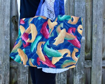 May include: A blue tote bag with a colorful fish pattern. The fish are in shades of yellow, green, red, and blue.