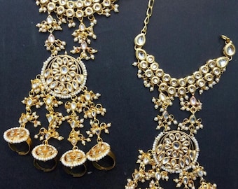 May include: A pair of gold-tone, ornate, hand jewellery sets with pearl accents. Each set features a ring with a circular design and a dangling chain with a larger circular design.