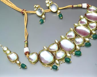 May include: A white and pink gemstone necklace with green accents. The necklace is made of gold and has a traditional Indian design. It comes with a matching maang tikka.