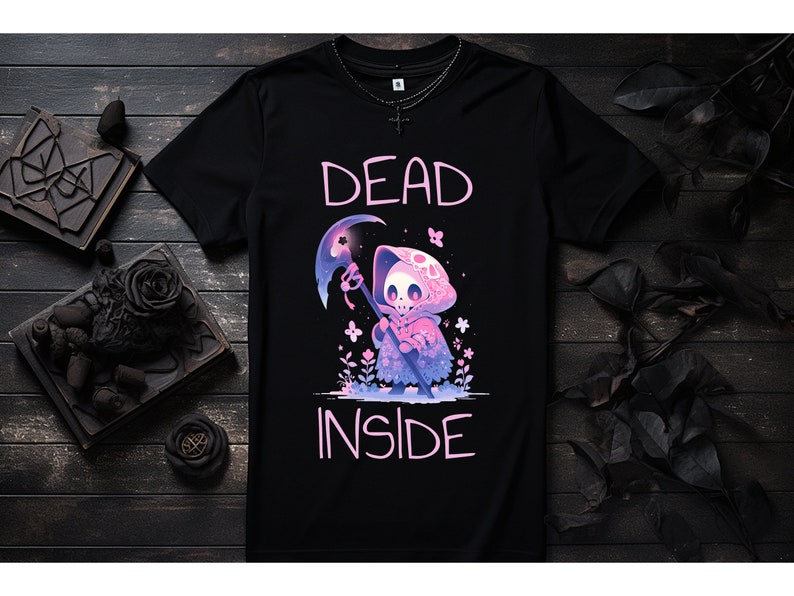 Puede incluir: Camiseta negra con un gr&aacute;fico rosa de un esqueleto de dibujos animados que lleva una capa con capucha y sostiene una guada&ntilde;a. El texto "DEAD INSIDE" est&aacute; impreso en rosa debajo del gr&aacute;fico.