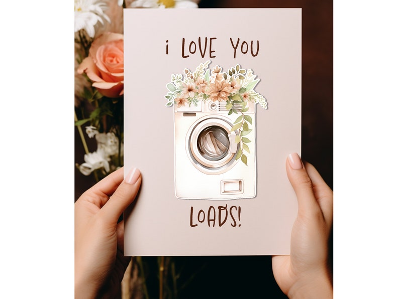 May include: A white card with a watercolor illustration of a washing machine with flowers on top. The card says "i love you loads!"