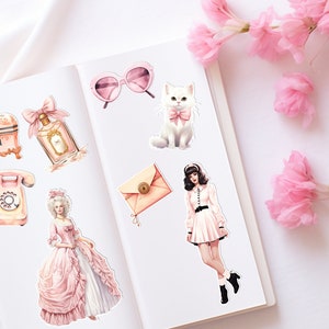 May include: A set of pink and white stickers featuring a vintage telephone, a perfume bottle, a jewelry box, a cat, a woman in a pink dress, a woman in a white dress, and a pink envelope.
