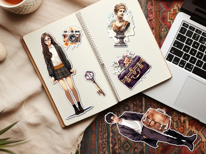 Pode incluir: Um caderno com v&aacute;rios adesivos, incluindo uma mulher de &oacute;culos, uma c&acirc;mera, uma chave, um busto de mulher, uma mala com flores e um homem de terno. O caderno est&aacute; em um tapete estampado.