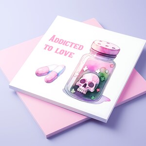 Puede incluir: Una tarjeta blanca con el texto "Addicted to Love" en letras rosas. Un frasco de vidrio con una tapa rosa y una calavera en su interior est&aacute; lleno de caramelos rosas, verdes y blancos. Dos pastillas rosas est&aacute;n sobre la tarjeta.