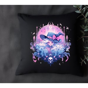 Puede incluir: Una almohada negra con una ilustraci&oacute;n colorida de una bruja con el pelo largo y blanco que lleva un sombrero rosa y azul con un lazo. La bruja est&aacute; rodeada de flores rosas y azules y una calavera.