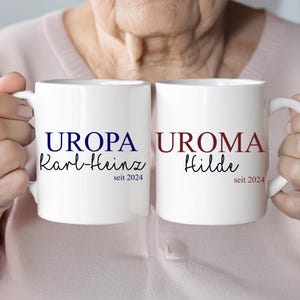 Könnte beinhalten: Zwei weiße Tassen mit blauem und rotem Text. Die Tasse links sagt "UROPA Karl-Heinz seit 2024" und die Tasse rechts sagt "UROMA Hilde seit 2024".