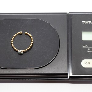Puede incluir: Un anillo de oro con una piedra verde en una b&aacute;scula digital que marca 1,1 gramos.