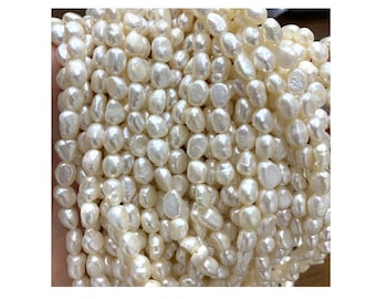 May include: A strand of white freshwater pearls, each pearl is a slightly irregular, rounded shape. The pearls are arranged in a loose pile, showing the variation in size and shape.