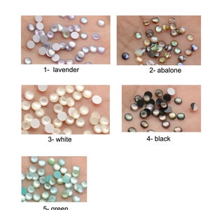 Puede incluir: Surtido de 5 colores diferentes de adornos redondos de aspecto perlado. Los colores son lavanda, abalone, blanco, negro y verde.