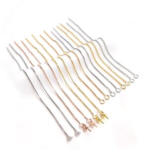 May include: A set of 14 earring chain extenders in silver, gold, and rose gold. The chains are delicate and have a box chain design. The extenders are perfect for adding a touch of elegance to any earring.