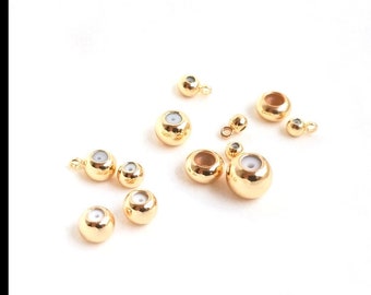 May include: Assortment of gold-toned metal bead caps with a small hole in the center. The bead caps are various sizes and are scattered on a white surface.