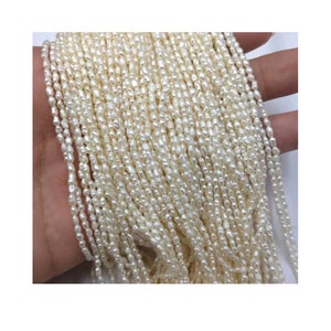 May include: A strand of white freshwater pearls, each pearl is small and irregular in shape. The pearls are strung on a thin thread and are ready to be used for jewelry making.