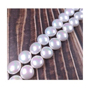 May include: A strand of white iridescent round beads, with a pearlescent finish, on a wooden surface.