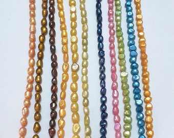 May include: Assortment of 10 strands of baroque freshwater pearls in various colors, including gold, brown, yellow, green, blue, and pink.