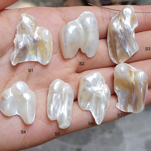 Puede incluir: Siete perlas barrocas blancas con matices iridiscentes, etiquetadas de S1 a S7. Las perlas tienen una forma irregular y un aspecto natural y orgánico.