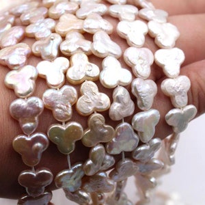 May include: A strand of white and cream-colored pearl beads, each bead is shaped like a clover with three rounded lobes.