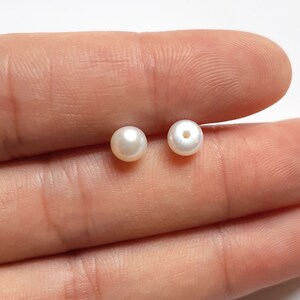 May include: Two white pearl beads with a hole drilled through the center.