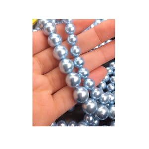 以下が含まれることがあります： 薄い水色の真珠のビーズの糸。ビーズは丸く、滑らかで光沢のある仕上がりです。