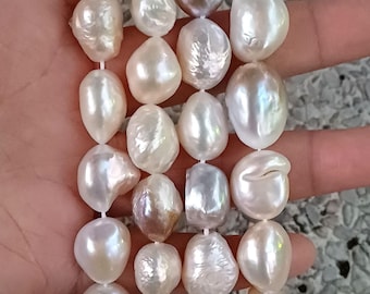 May include: A strand of white baroque pearls with a few iridescent pearls. The pearls are strung on a white cord and are of varying sizes.
