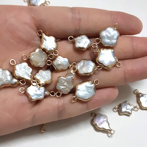 Puede incluir: Una colección de abalorios de perlas barrocas blancas con anillas de salto doradas. Las perlas tienen una forma irregular y un aspecto natural y orgánico. Los abalorios son perfectos para añadir un toque de elegancia a los proyectos de joyería.