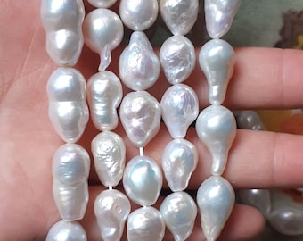 May include: A strand of white baroque pearls with an iridescent sheen. The pearls are strung on a white thread and are of varying sizes and shapes.