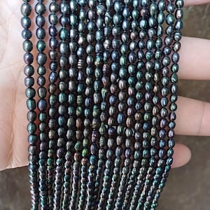 以下が含まれることがあります： 黒く虹色の淡水パールが連なったもの。 楕円形のパールは、控えめな光沢があります。 ストランドは一緒に保持され、サイズと色の自然なバリエーションを示しています。 ジュエリー作りに最適です。