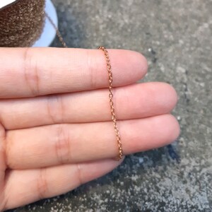 May include: A close-up of a gold chain necklace. The chain is delicate and has a fine, linked design.
