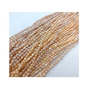May include: A strand of small, irregular, off-white and peach-colored freshwater pearls. The pearls are strung on a thin thread and are approximately 3-4 mm in size.