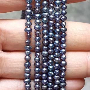 May include: A strand of dark blue freshwater pearls. The pearls are round and have a slight iridescent sheen.