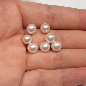 Puede incluir: Una colección de ocho perlas redondas blancas, mostradas en una mano.