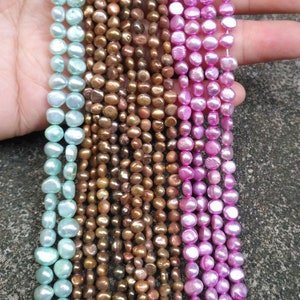 Pode incluir: Um fio de pérolas de água doce azul claro, um fio de pérolas de água doce castanhas e um fio de pérolas de água doce cor-de-rosa.