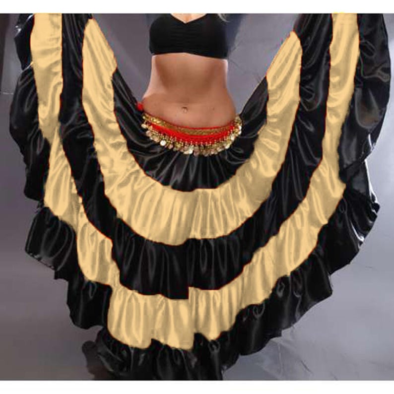 May include: A black and gold satin dance skirt with multiple layers and ruffles. The skirt is designed for belly dancing or other performance styles.
