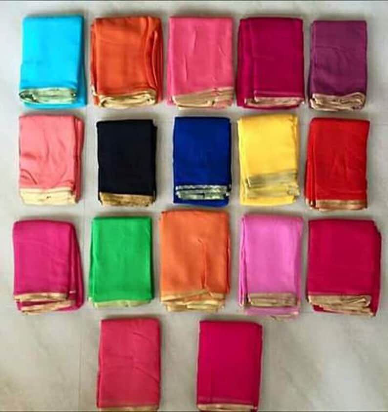 May include: A collection of 16 folded fabric squares in various colors, including blue, orange, pink, red, purple, black, yellow, green, and white. Each square has a gold trim around the edges.