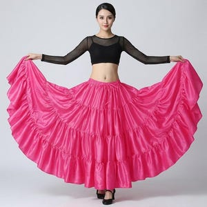Puede incluir: Una falda de baile rosa vibrante, con volantes y diseño escalonado. Se combina con un top corto negro y una blusa transparente de manga larga. Adecuada para actuaciones de baile.