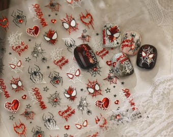 Könnte beinhalten: Ein Bogen mit selbstklebenden Nagelstickern mit roten und schwarzen Spinnenmotiven, darunter Spinnennetze, Spinnenaugen, Herzen sowie der Schriftzug "Spider-Man" und "Ghost Power", neben vier bereits verzierten künstlichen Fingernägeln.