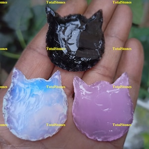 Könnte beinhalten: Drei katzenförmige Pfeilspitzen aus verschiedenen Glassorten. Die Pfeilspitzen sind schwarz, blau und rosa.