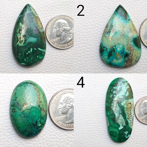 Puede incluir: Cuatro piedras preciosas pulidas con diversas formas y patrones. Las piedras muestran una mezcla de tonos verdes, turquesas y marrones. Se coloca una moneda de veinticinco centavos estadounidense junto a cada piedra para comparar el tama&ntilde;o. Las piedras preciosas son probablemente para la fabricaci&oacute;n de joyas o coleccionar.