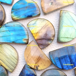 Peut inclure: Une collection de cabochons de labradorite en pierres précieuses dans différentes nuances de bleu, vert et or. Les cabochons sont tous en forme de demi-lune et ont une finition lisse et polie.