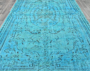 Puede incluir: Una alfombra rectangular turquesa desgastada con un intrincado patrón floral descolorido. La alfombra presenta un diseño de medallón central y un borde oscuro. La paleta de colores de la alfombra incluye tonos de turquesa, marrón y negro.