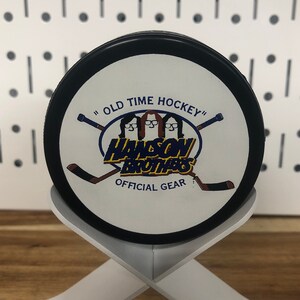 Chiefs hockey puck back side displayed on edge on a white stand that looks like crossed hockey sticks