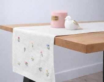 Camino de mesa de lino crudo con pequeñas flores primaverales bordadas y detalles en tonos pastel. Decoración clásica moderna para el hogar.
