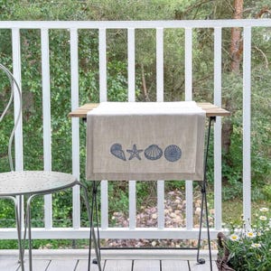 Lino beige decorativo con bordes de conchas marinas en azul.