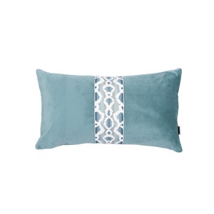 May include: A rectangular turquoise cushion with a central patterned band. The band features a white and grey geometric design. The cushion is made of a soft, velvety material, ideal for adding a touch of elegance to any room.