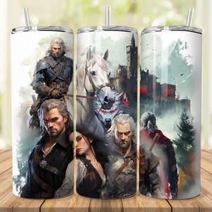 Op de afbeelding: Drie roestvrijstalen bekers met een witte achtergrond en een kleurrijk beeld van personages uit het videospel The Witcher. De afbeelding bevat een wit paard, een man met een zwaard, een vrouw met lang bruin haar en een kasteel op de achtergrond.