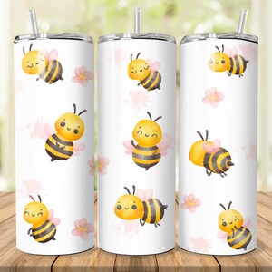 May include: Three stainless steel tumblers with a white background and a repeating pattern of cartoon bees with pink flowers. The bees are yellow and black with a cute smiling face.