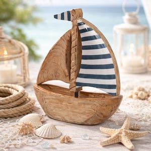 Puede incluir: Velero de madera con vela y bandera a rayas azules y blancas. El barco está sobre una superficie de madera blanca con conchas, una estrella de mar y una cuerda. El fondo presenta una escena de playa.