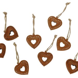 May include: Eight rustic brown metal heart-shaped ornaments with a smaller heart cut out in the centre. Each heart has a jute twine hanger.